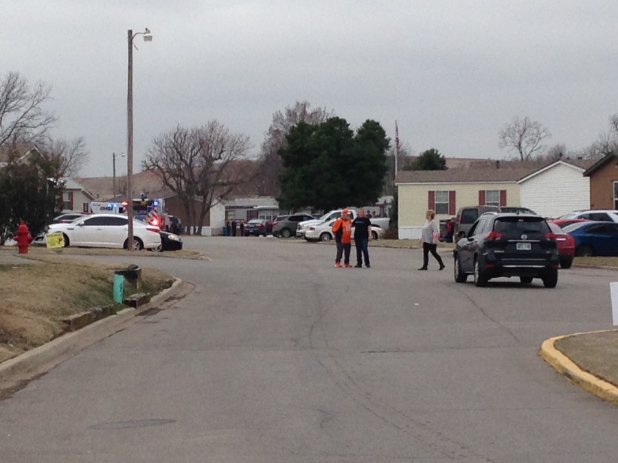 This is a picture of the scene of a reported shooting in southwest Oklahoma City. The image is people standing in a road with homes behind them. 