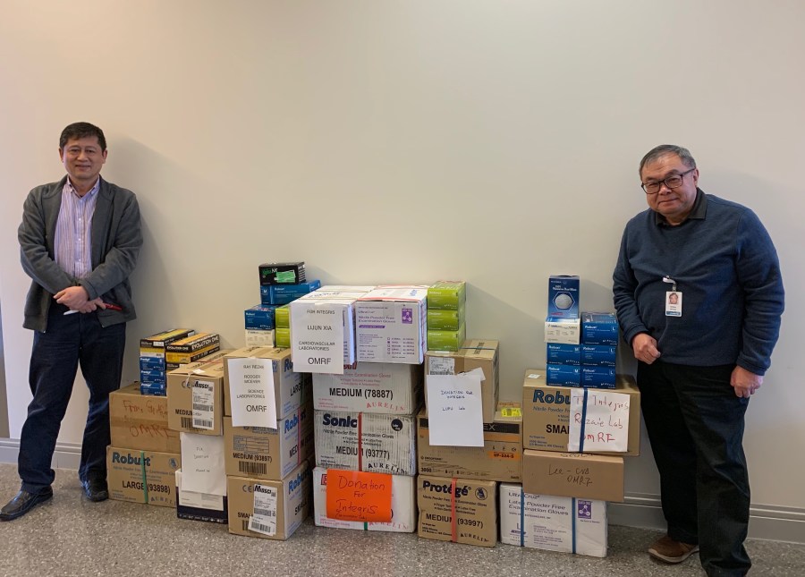 Lijun Xia, M.D., Ph.D., and Hendra Setiadi, Ph.D., with the laboratory gloves the Oklahoma Medical Research Foundation donated to Integris Baptist Medical Center for use during the COVID-19 coronavirus pandemic. March 2020