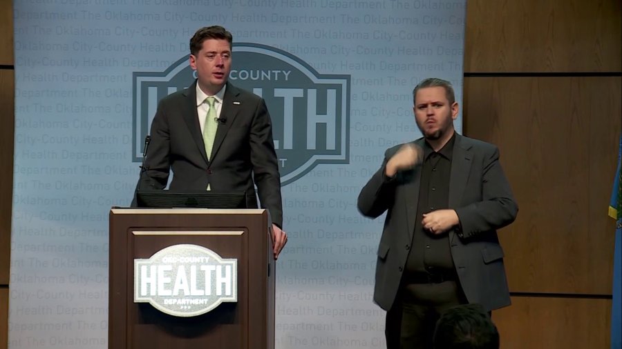 OKC Mayor David Holt talking at podium with sign language interpreter by his side