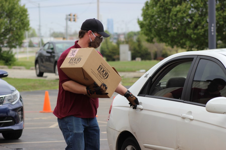 Man in mask puts box of food into car